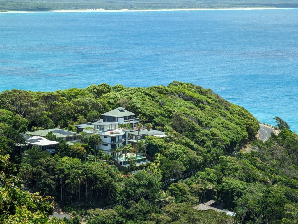 Stunning aerial view of houses nestled in lush greenery by the Byron Bay coastline.