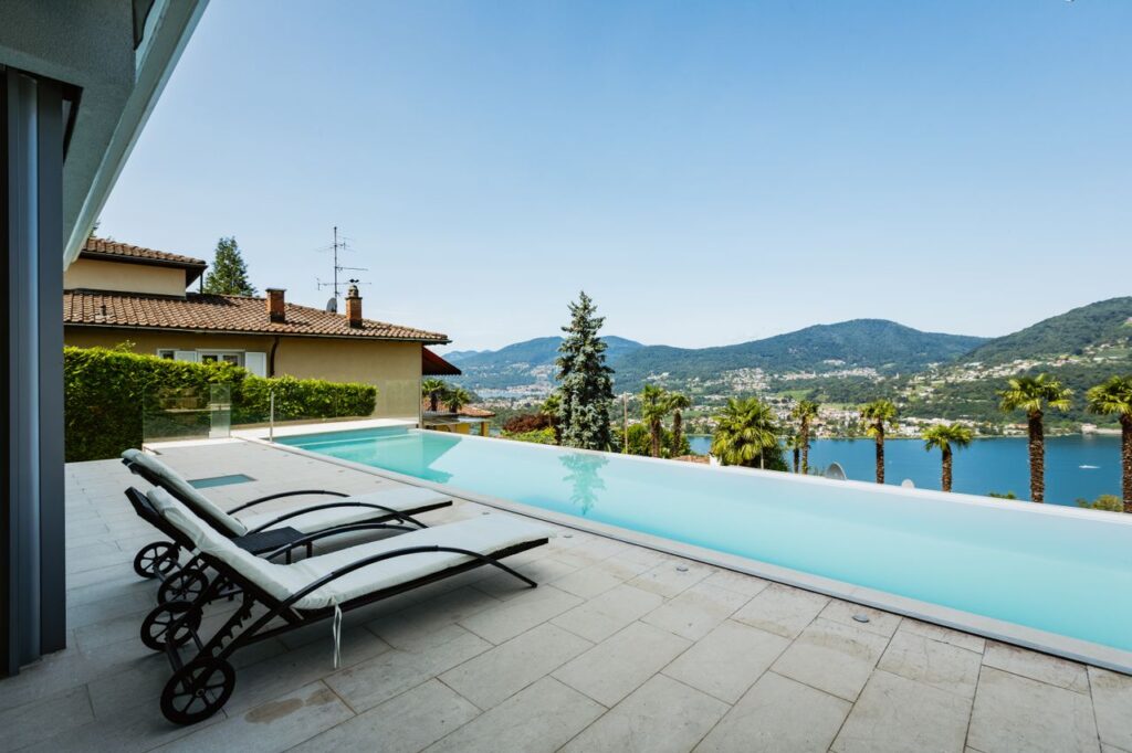 Elegant lakeside infinity pool with stunning mountain and water views, perfect for relaxation and summer leisure.